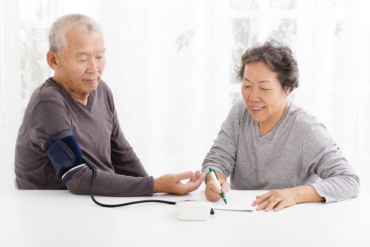 A woman taking a man's blood pressure