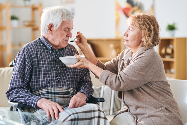 A woman caregiver feeding an older man