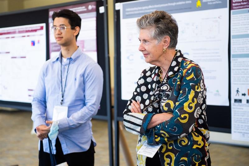 Suzanne Labarge listens to a research poster presentation beside a McMaster trainee.
