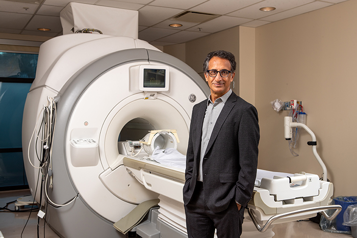Dr. Parminder Raina stands in front of an MRI machine.