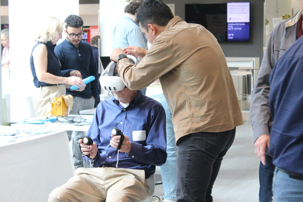 Mac engAGE attendee engages with exergames with help from Dr. John E. Muñoz