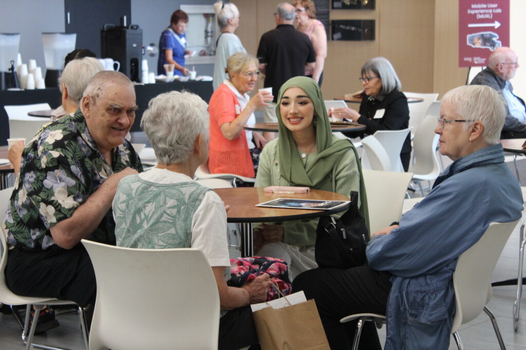Mac engAGE attendees and student volunteer conversing at table