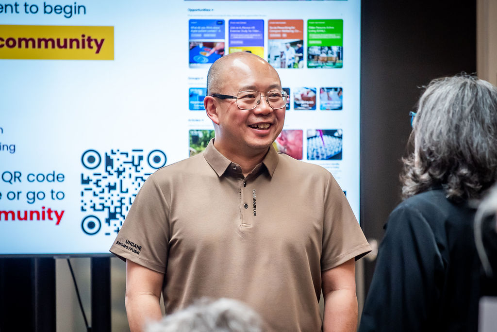 Qiyin Fang speaks to someone in front of a television screen