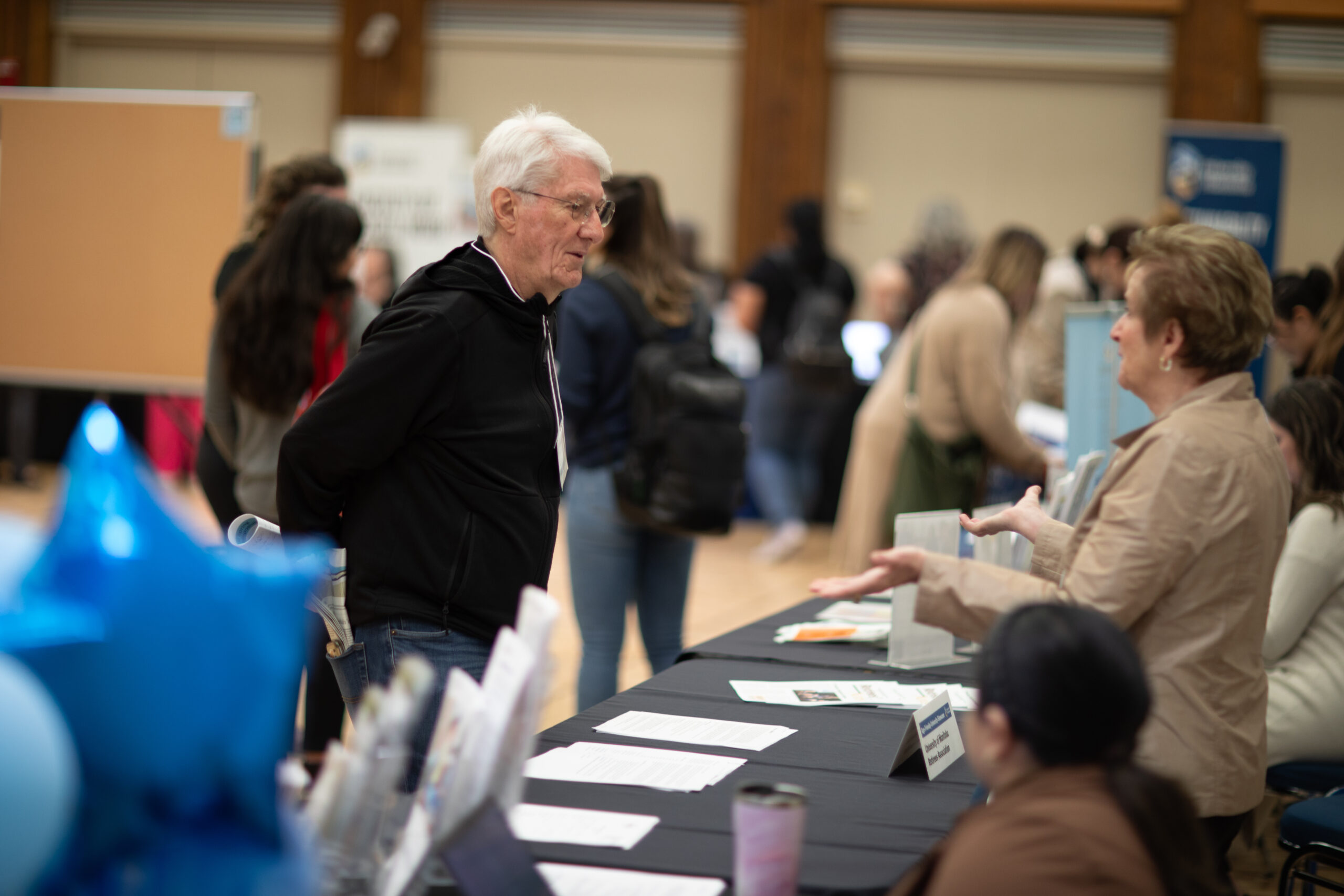 Older adult speaking with a person at an event table